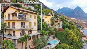Un edificio de varios pisos con balcones, piscina y montañas al fondo.