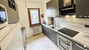 Cocina compacta con horno empotrado, estufa, pileta y ventana con vista al exterior.