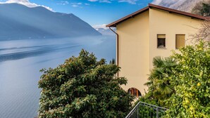 Una casa costera con vista a un lago tranquilo y montañas al fondo.
