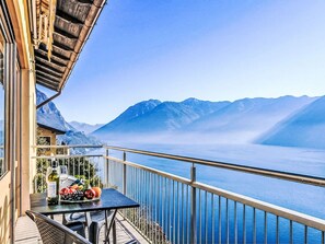 Un balcone con un tavolo apparecchiato per un pasto, con vista su un lago e montagne.