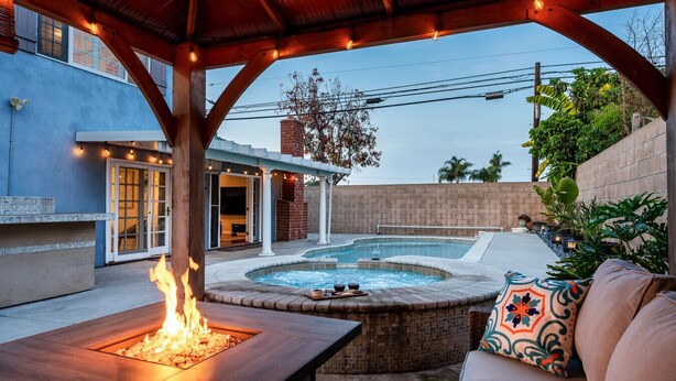 A backyard with a hot tub, a fire pit, and outdoor seating.