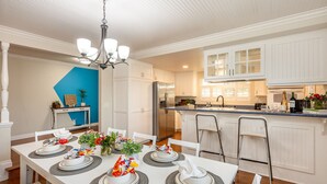 A modern kitchen with white cabinetry, a stainless steel refrigerator, and a dining area set for a meal.