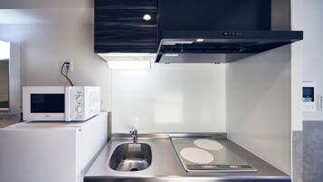 A modern kitchen with a microwave, sink, and stainless steel countertop.