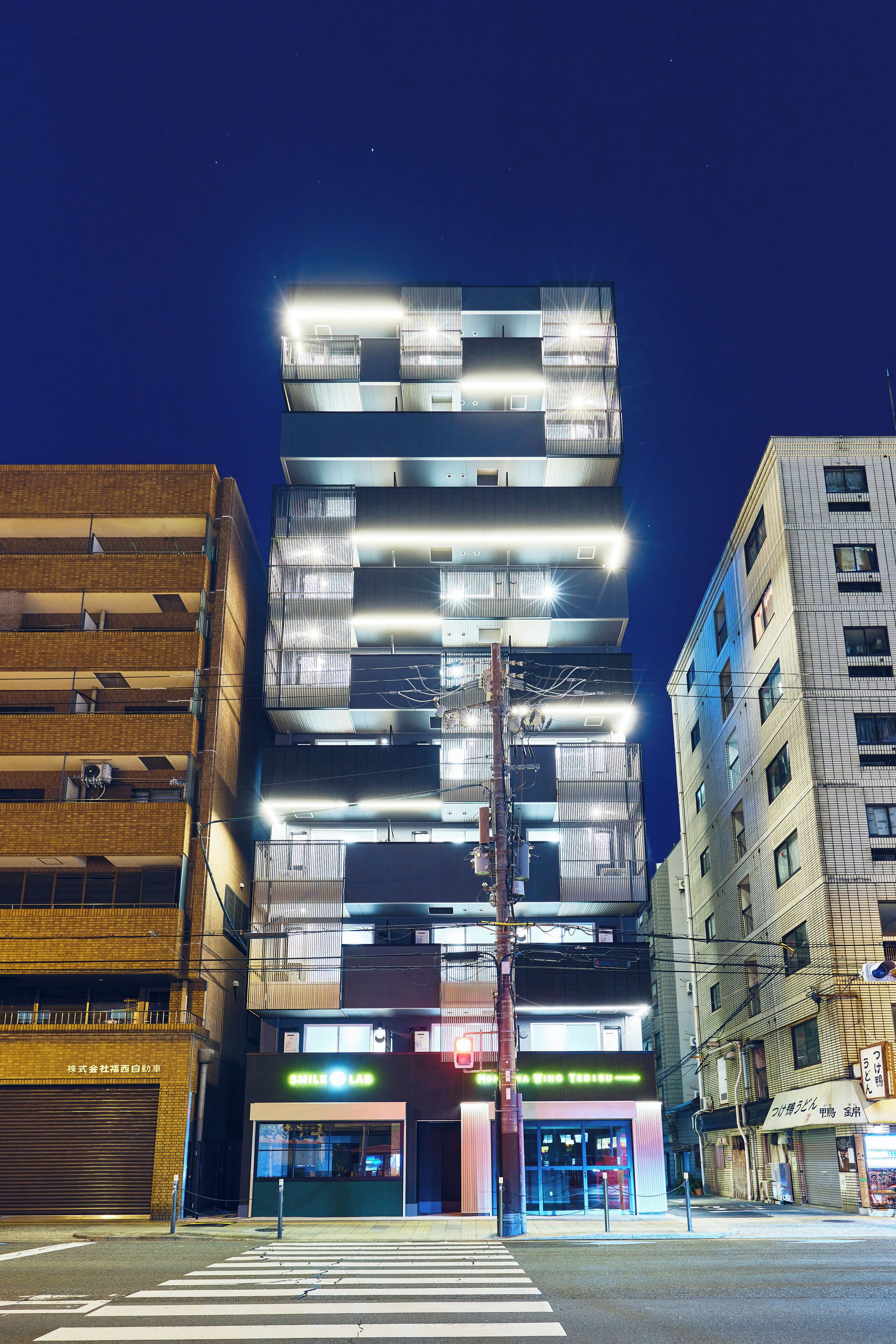 A multi-story building with illuminated windows and a ground-level entrance.