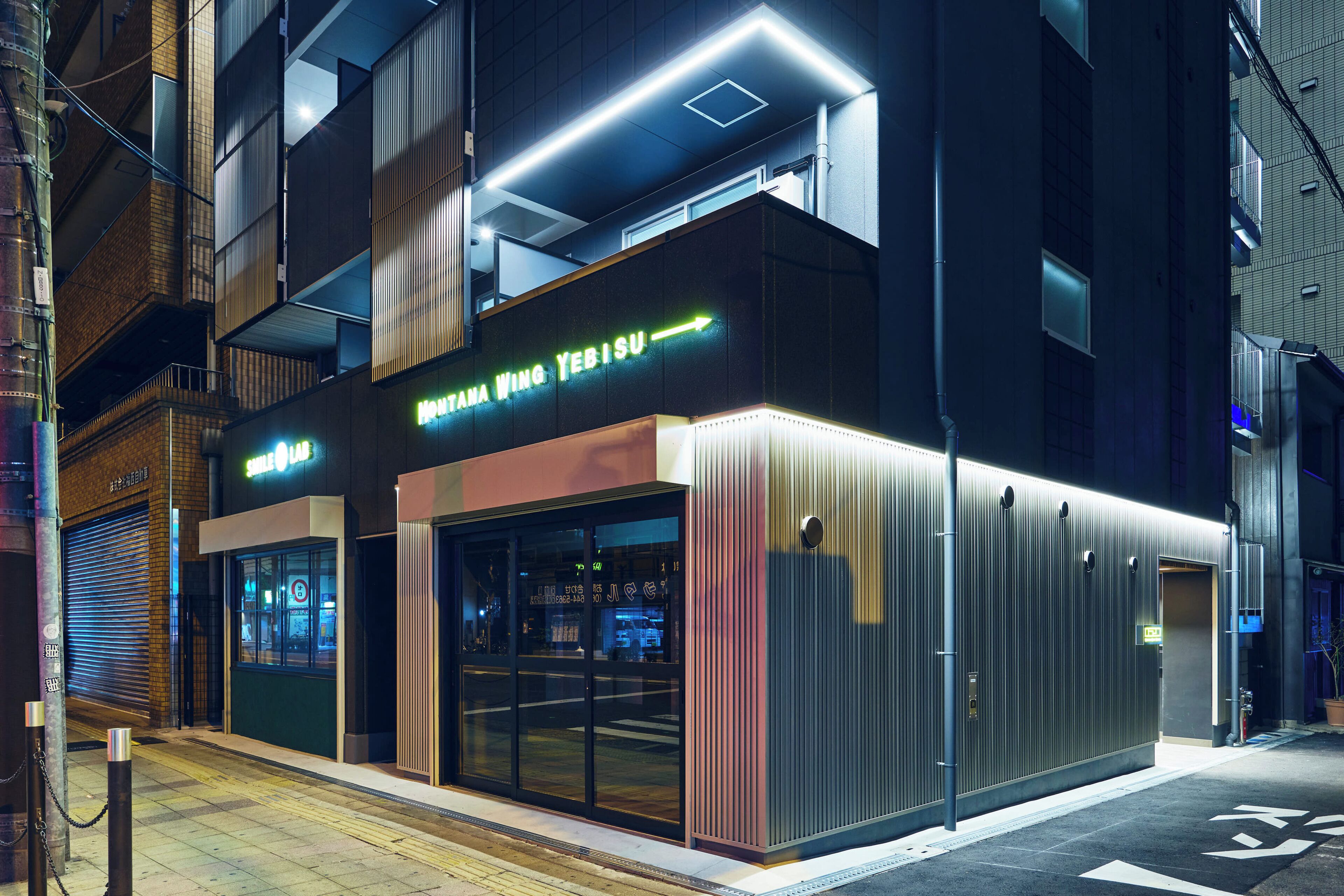 A modern building with a neon sign for 'Yebisu' and a visible entrance.