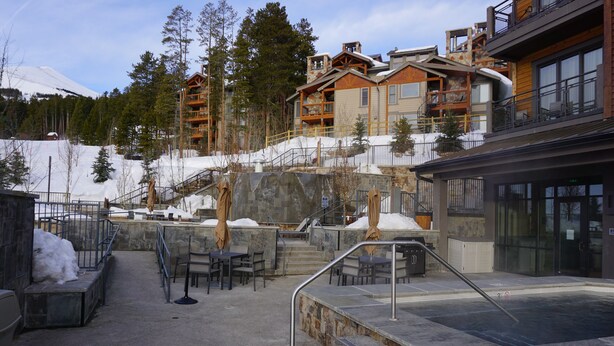 Ein Skigebiet mit Außenbestuhlung, einem Whirlpool und Holzhäusern mit Balkonen.