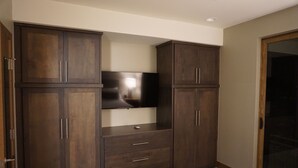 Ein Schlafzimmer mit großem Kleiderschrank, Flachbildfernseher und einer Schiebetür zum Balkon.