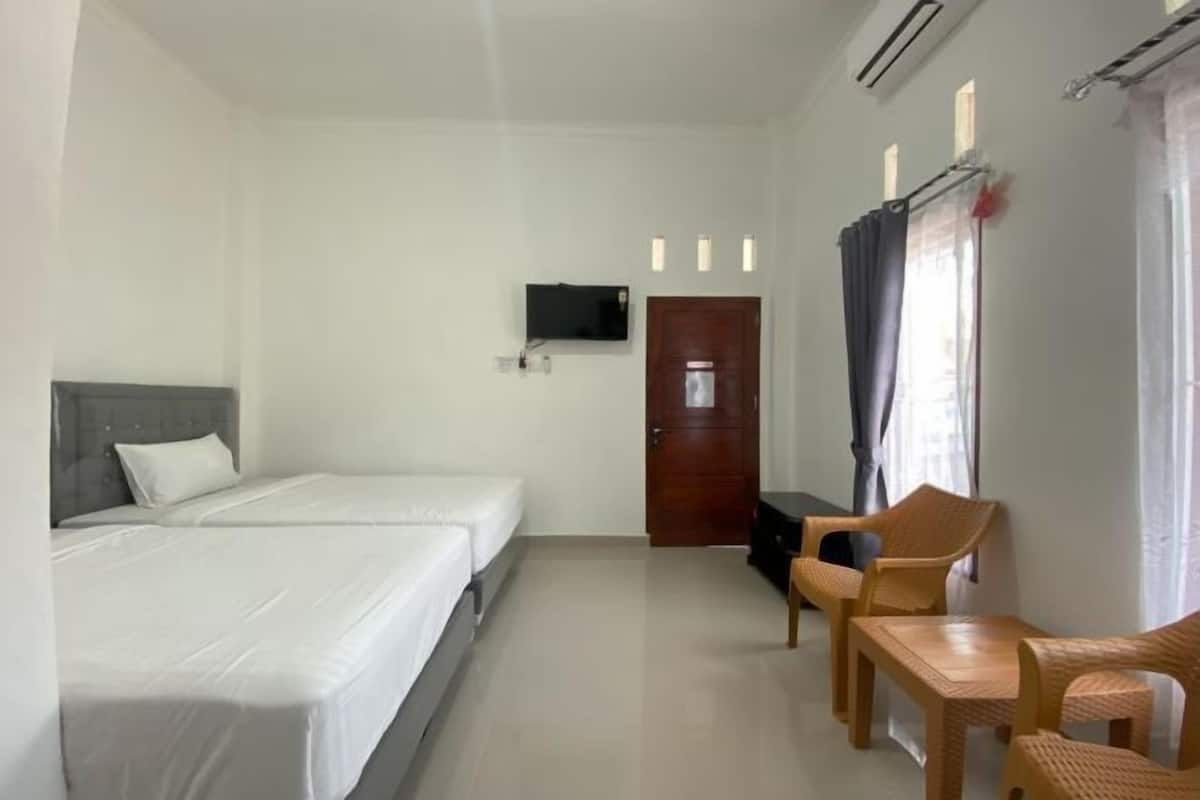 A hotel room with two beds, a TV, a desk, and a chair.