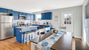 Una cocina moderna con armarios azules, electrodomésticos de acero inoxidable y una isla central con taburetes de bar.