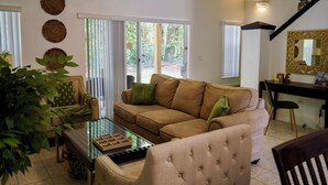 Un salon avec un canapé beige, une table basse en verre et une plante verte.
