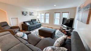 A modern living room with a sectional sofa, a recliner, a small sofa, and a TV stand.