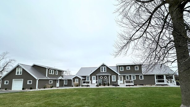 A large, two-story house with a front porch, a garage, and a well-maintained lawn.