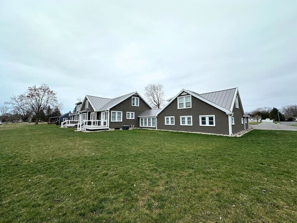A two-story house with a large front lawn, a covered porch, and a garage.