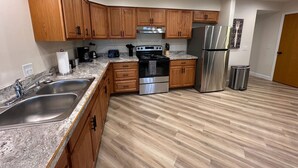 A modern kitchen with wooden cabinets, stainless steel appliances, and a granite countertop. - Modern Riverbend Suites - 2BR (Bay City)