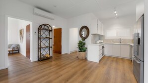 Una cocina amplia con suelo de madera, armarios blancos, horno empotrado y refrigerador.