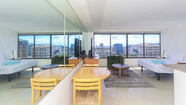 Una sala moderna con comedor, ventanas amplias y vista a la ciudad.