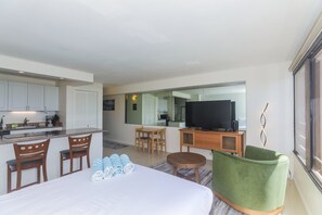 A modern hotel room with a bed, a TV, a desk, and a kitchen area. - Experience the vibrant energy of Waikiki from the comfort of Discovery Bay (Honolulu)