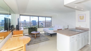Una habitación de hotel moderna con un ventanal grande, una cama, un comedor y una cocina.