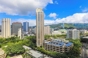A high-rise building with multiple floors, surrounded by other tall buildings and lush greenery. - 2-Bedroom Ocean View, Perfect Location in Waikiki! (Honolulu)