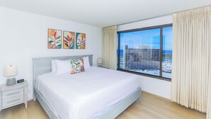 Una camera d'hotel con un letto grande, un comodino, una lampada e una finestra con tende.