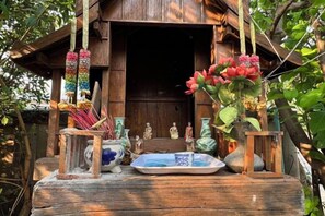 A wooden table with various items including a vase with flowers, a plate, and figurines. - Luxurious Living by the River Hannah Villa (Chiang Mai)