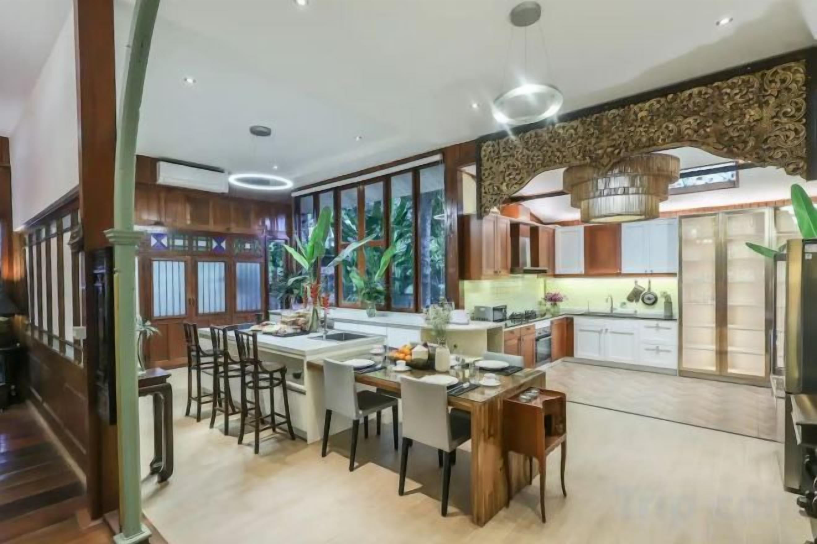 A modern kitchen with a central island, bar stools, and a dining area.