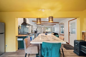 Una cocina moderna con una isla central, luces colgantes y una zona de comedor con sillas.