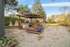 Un espacio al aire libre cubierto con un pérgola de madera, un jacuzzi y un contenedor azul.
