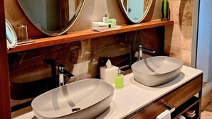 Un baño moderno con dos lavamanos ovalados grandes, un espejo sobre cada lavamanos y un mueble de tocador de madera.