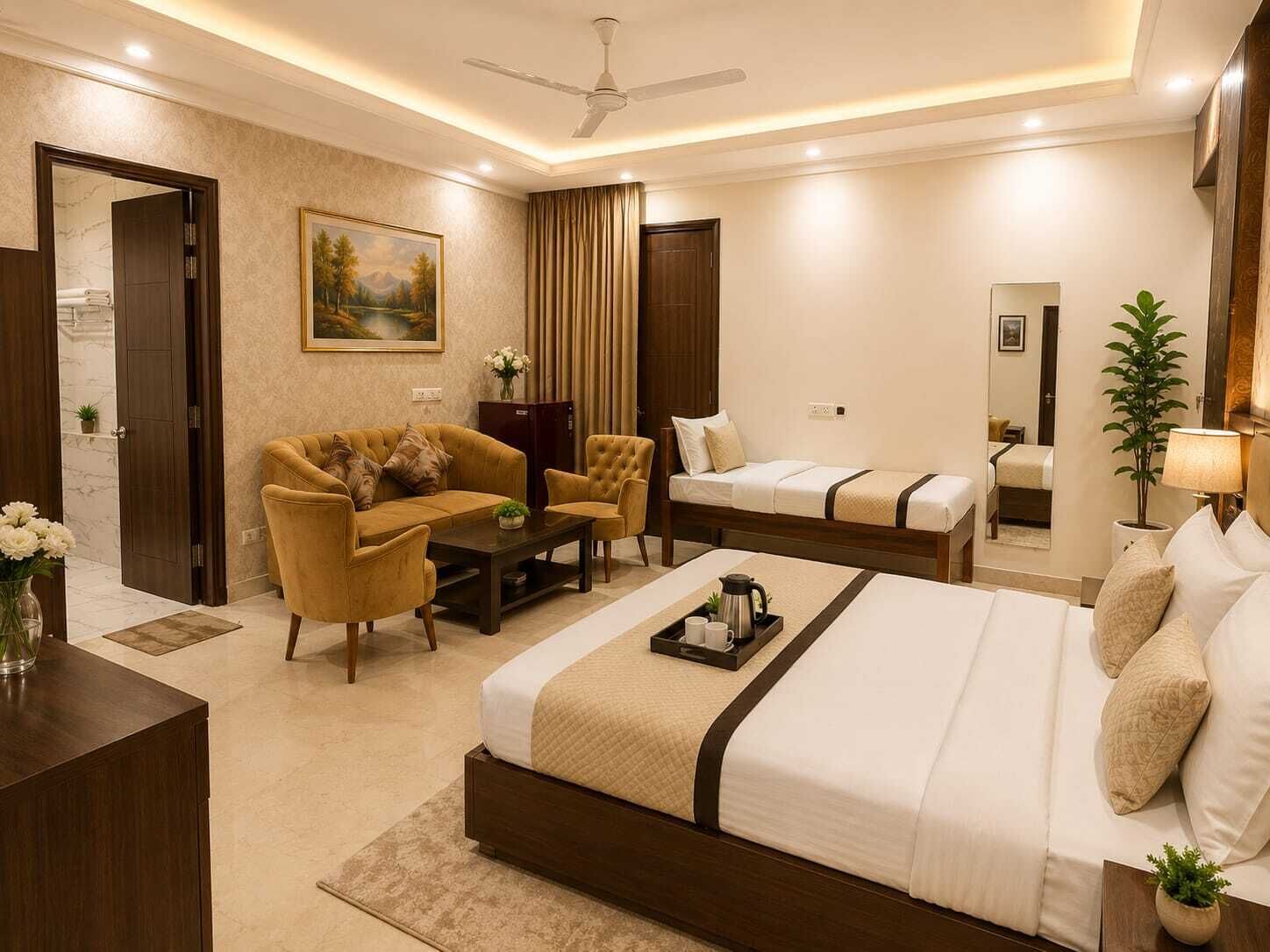 A hotel room with a bed, sofa, chairs, a coffee table, a painting, a mirror, and a ceiling fan.