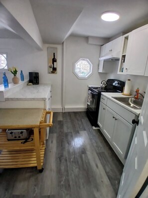 A compact kitchen with a wooden table, a built-in oven, and a window with a view.