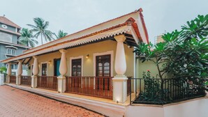 A colonial-style building with a tiled roof, large windows, and a balcony with a railing. - Baga Villa Harshita (Calangute)