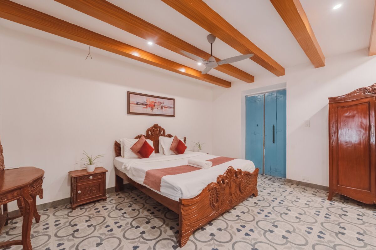 Un dormitorio con una cama de madera, una mesita de noche, un armario de madera y una puerta azul.