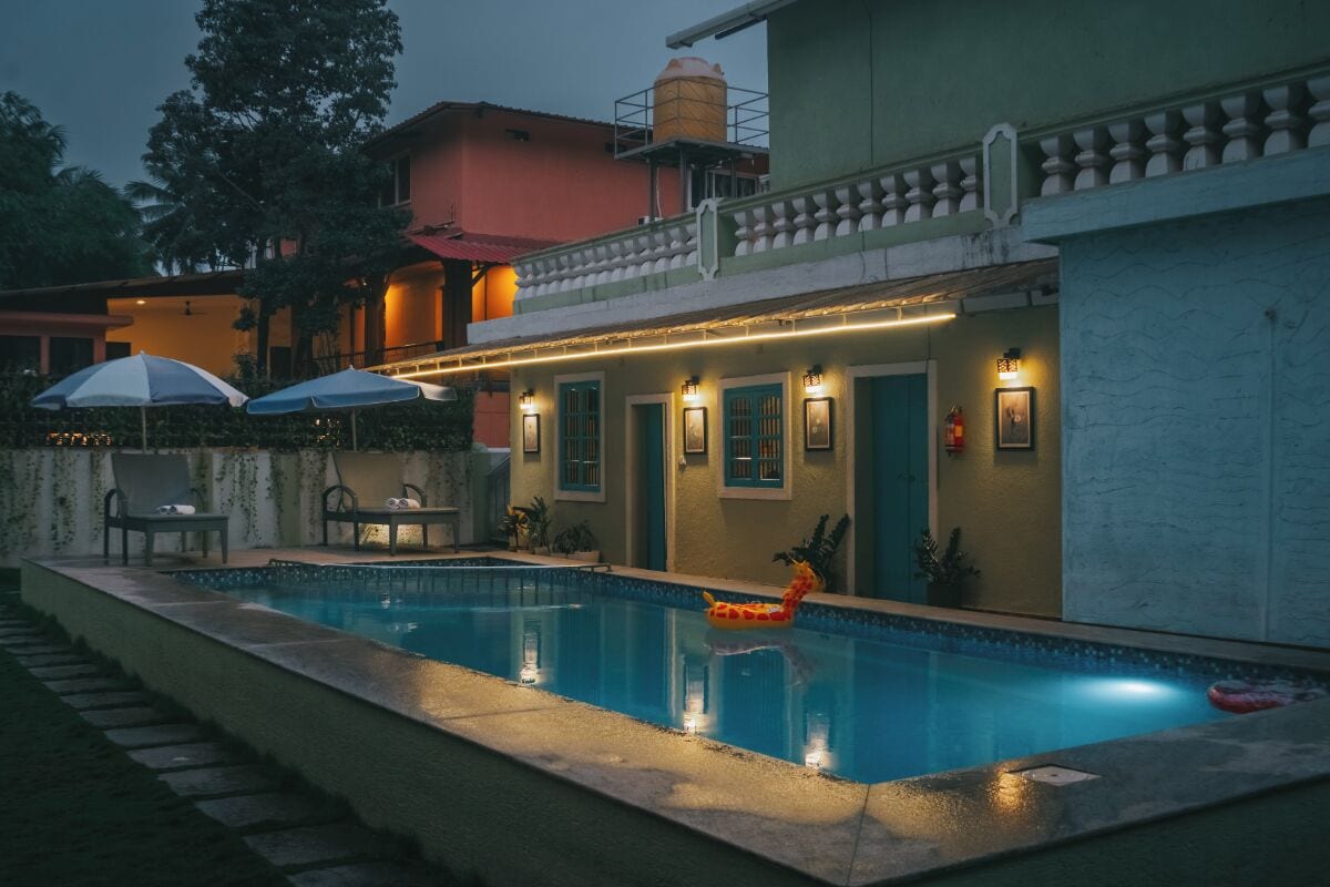 A swimming pool with a lounge area, umbrellas, and a giraffe float.