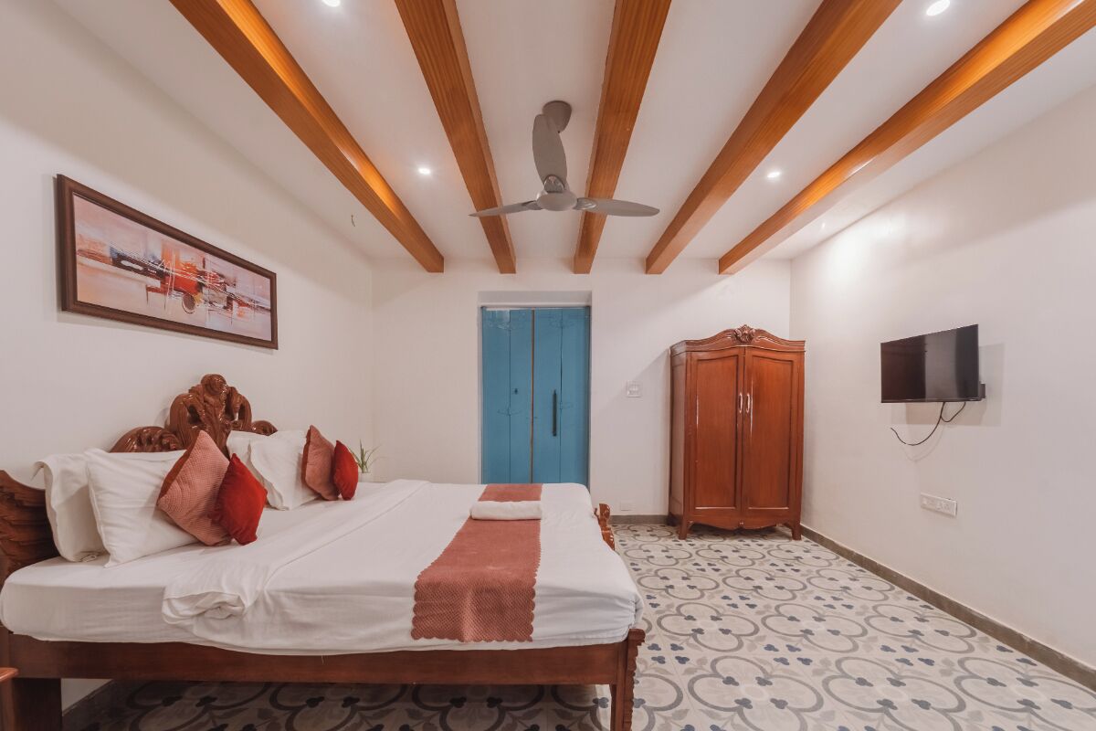 A bedroom with a bed, a ceiling fan, a wardrobe, a television, and a door.