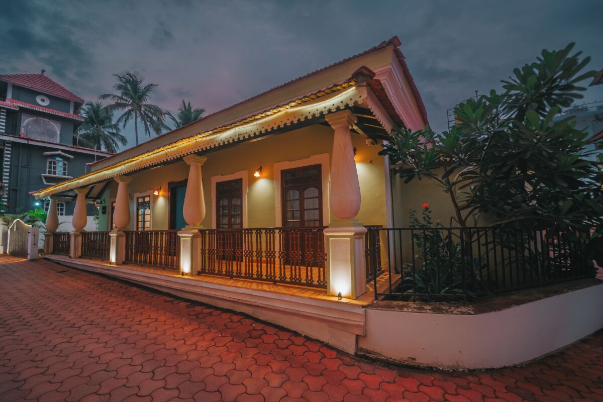 Un edificio de estilo colonial con balcón, ventanas amplias y un sendero adoquinado.