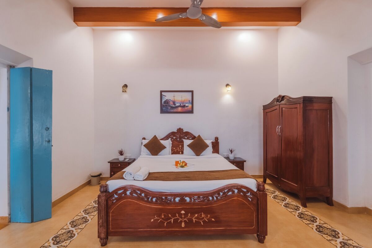 A bedroom with a wooden bed, a ceiling fan, a painting on the wall, and a wardrobe.