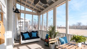 Eine überdachte Veranda mit einer hölzernen Bank, einer gepolsterten Sitzecke mit blauen Kissen und einem Blumentopf.
