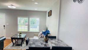 A living room with a glass-top coffee table, a sofa, and a dining area with chairs. - Cozy 2-bedroom townhome in charming Dallas with WiFi, AC (Dallas)