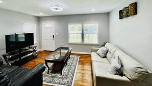 A living room with a flat-screen TV, a glass-top coffee table, a sofa, and a patterned rug. - Cozy 2-bedroom townhome in charming Dallas with WiFi, AC (Dallas)