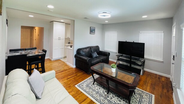 A living room with a sofa, coffee table, TV, and a dining area with chairs and a table. - Cozy 2-bedroom townhome in charming Dallas with WiFi, AC (Dallas)