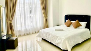 A hotel room with a large bed, a flat-screen TV, and a window with curtains. - D'Royale Desaru Homestay (Bandar Penawar)