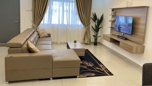 A modern living room with a sectional sofa, a flat-screen TV, and a ceiling fan. - D'Royale Desaru Homestay (Bandar Penawar)