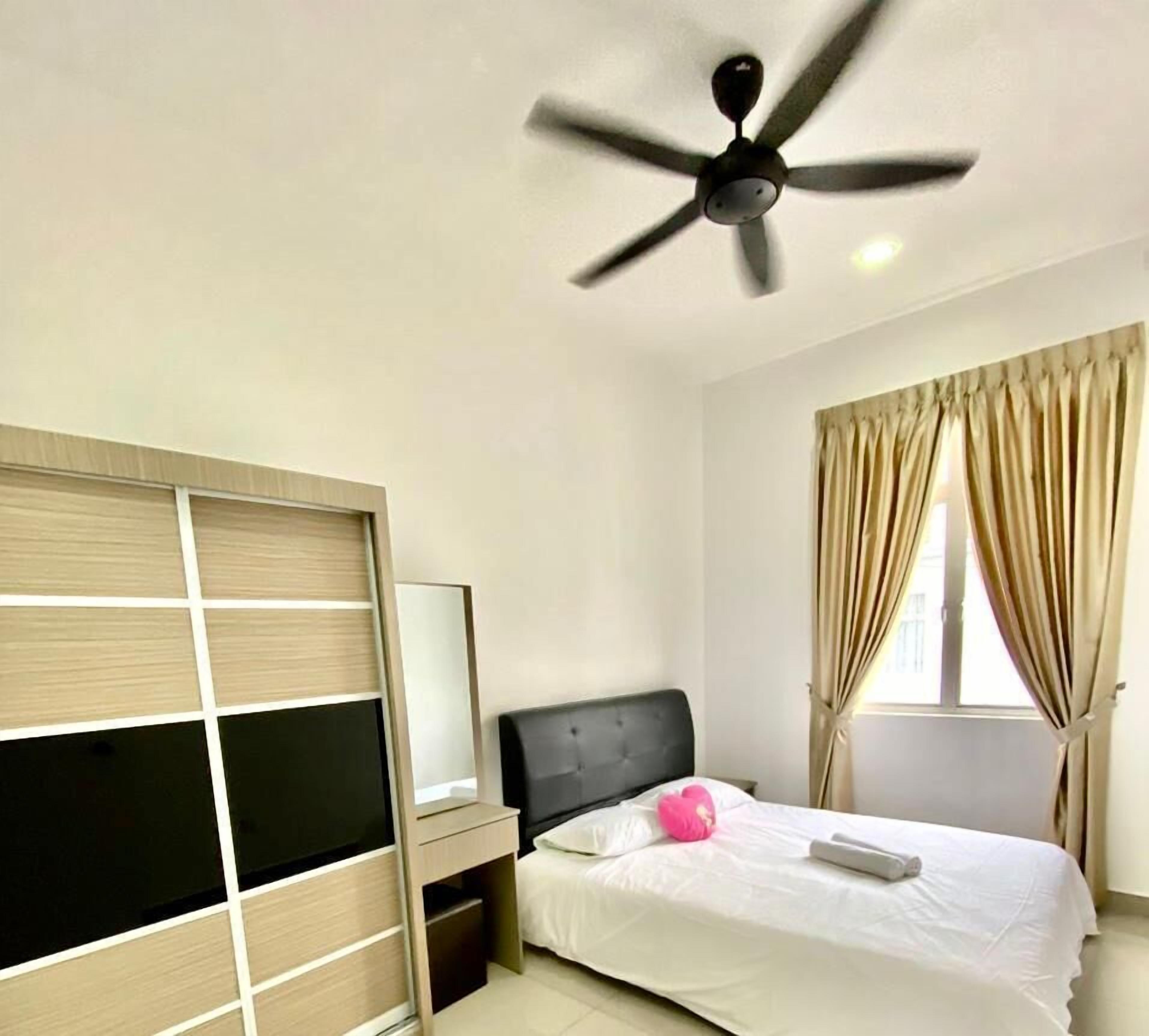 A bedroom with a bed, a ceiling fan, a window with curtains, and a bedside table.