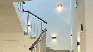 A staircase with a wooden finish, white walls, and a white door at the bottom. - D'Royale Desaru Homestay (Bandar Penawar)