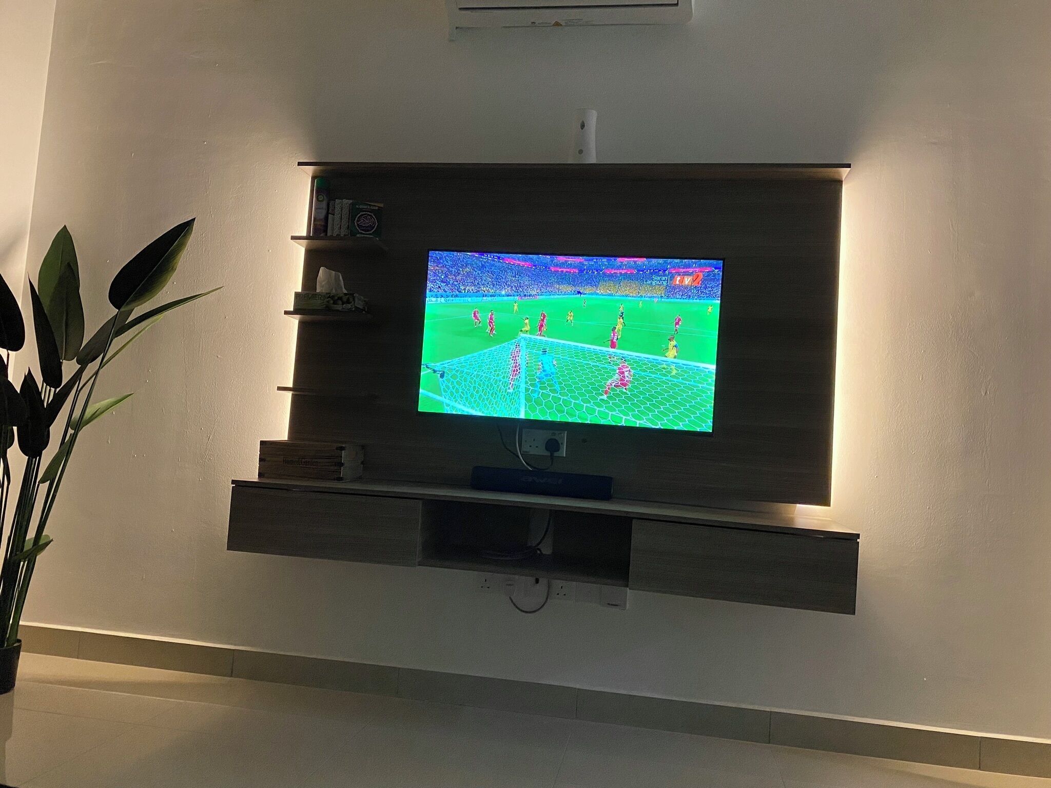 A flat-screen TV mounted on a wall with a shelf above it.