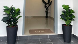 A hotel entrance with a number 33 sign, a glass door, two potted plants, and a doormat with "I ❤️ MI" written on it. - D'Royale Desaru Homestay (Bandar Penawar)
