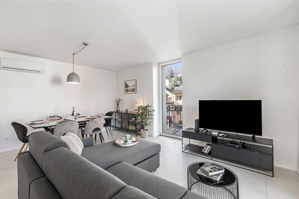 En moderne stue med en grå sofa, spiseplads og et fjernsyn på et sort tv-møbel.