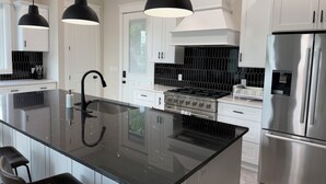 Una cocina moderna con una isla central, electrodomésticos de acero inoxidable e iluminación colgante.