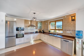 A modern kitchen with stainless steel appliances, a water dispenser, and a view of the outdoors.